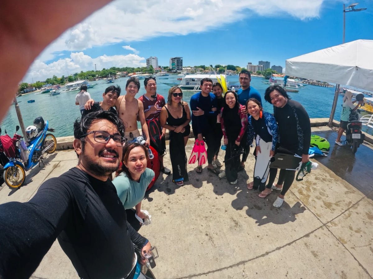 Full Scale employees in wetsuits and fins posed together on a pier after a free diving trip