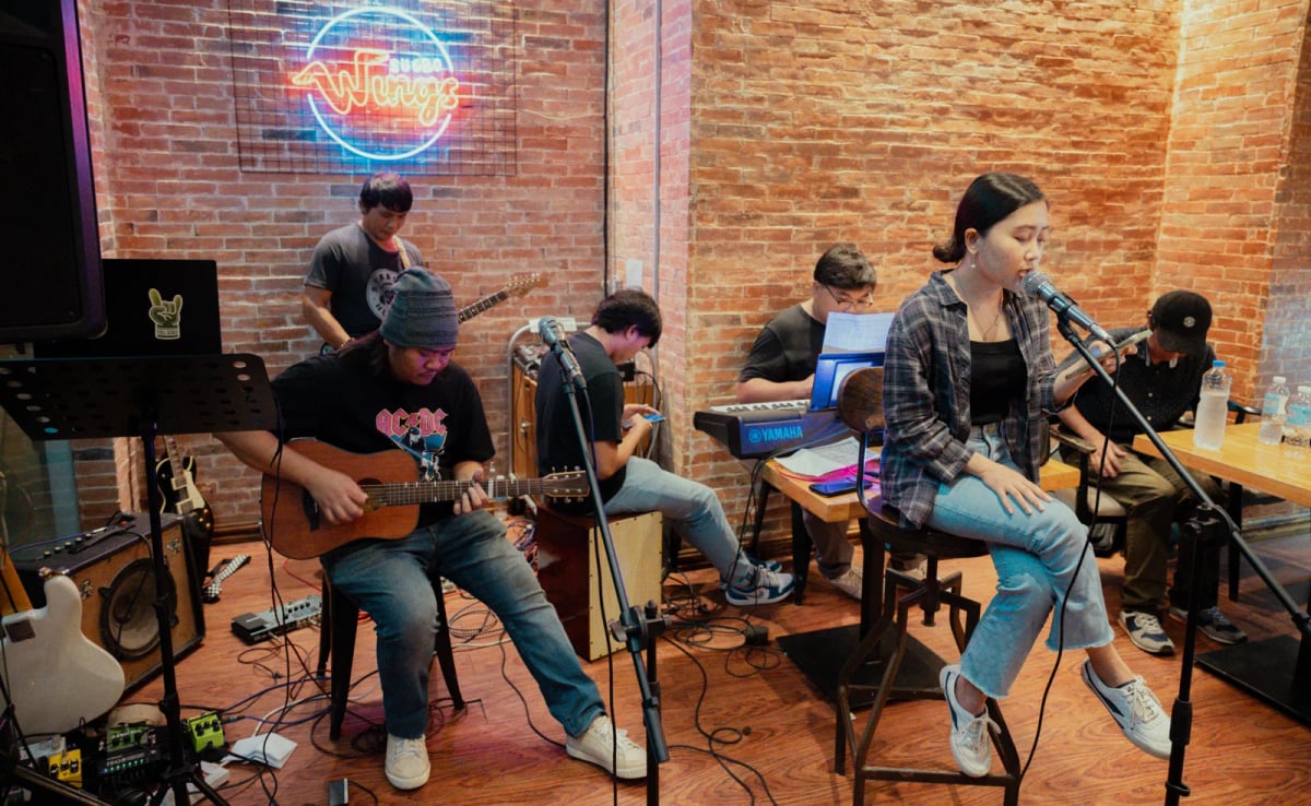 Members of the Full Scale music club performing live together, on guitar, keys, cajon and vocals