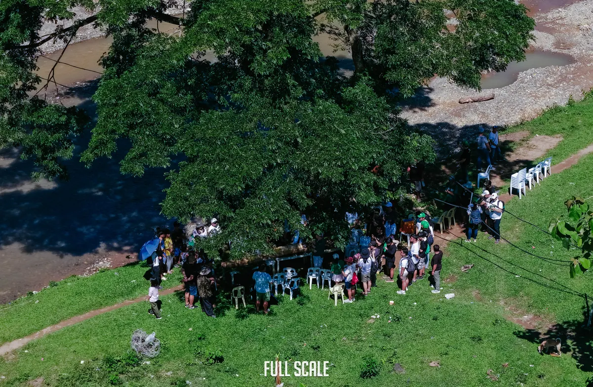 Volunteers gathered under the trees beside the Jaclupan river during the bamboo planting activity