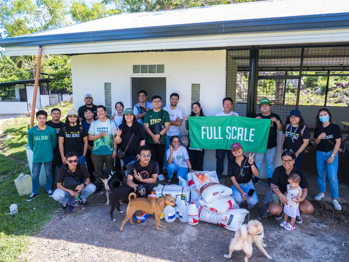 Full Scale volunteers holding the company banner with rescued dogs and donated supplies at Island Rescue Organization in Cebu
