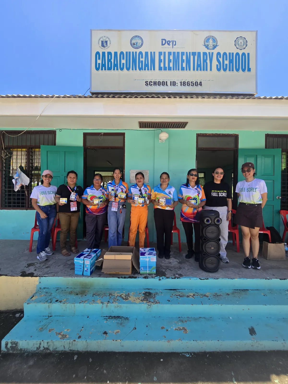 Local volunteers and children with donated school supplies outside a classroom on Cabilao Island, Bohol
